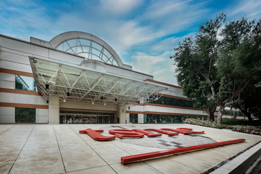 Exterior of a TSMC semiconductor factory with the company’s large red logo in front of the building.