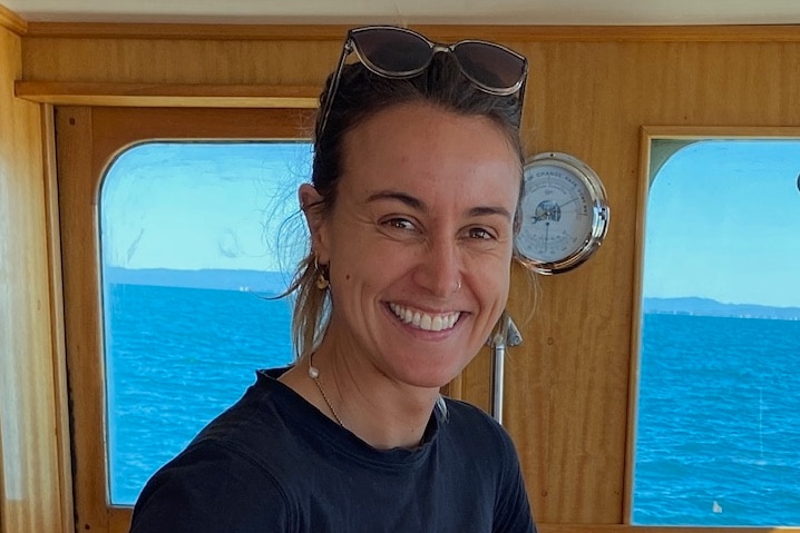 A woman with sunglasses on her head stands in the cabin of a boat. 