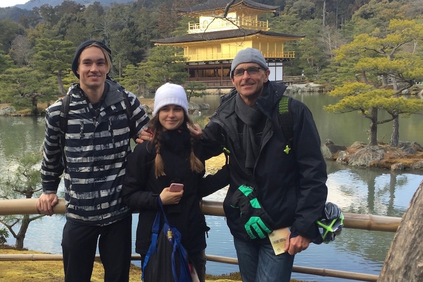 Greg is pictured with his family members while standing in front of a temple