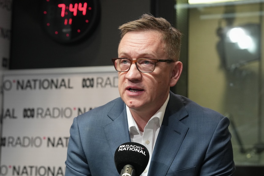 Julian Hill speaks into a microphone in a radio studio