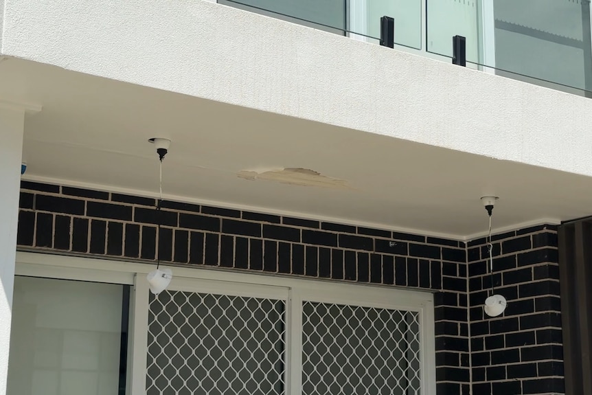 image of outdoor lights dangling from wires under balcony