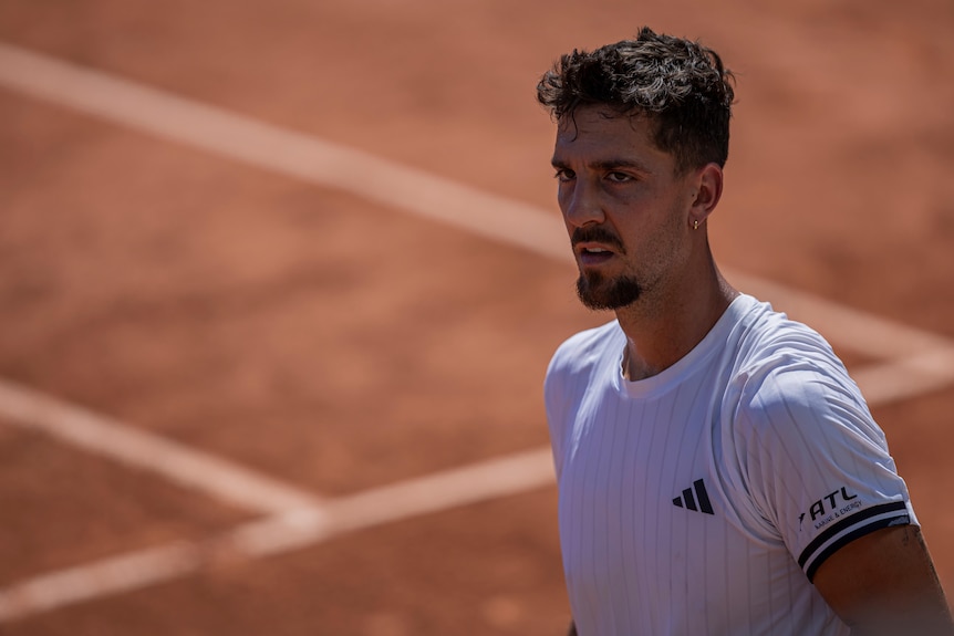 Male tennis player walking on clay court