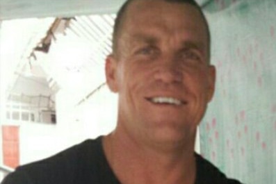 A Caucasian man in a black t-shirt smiles in a photo.