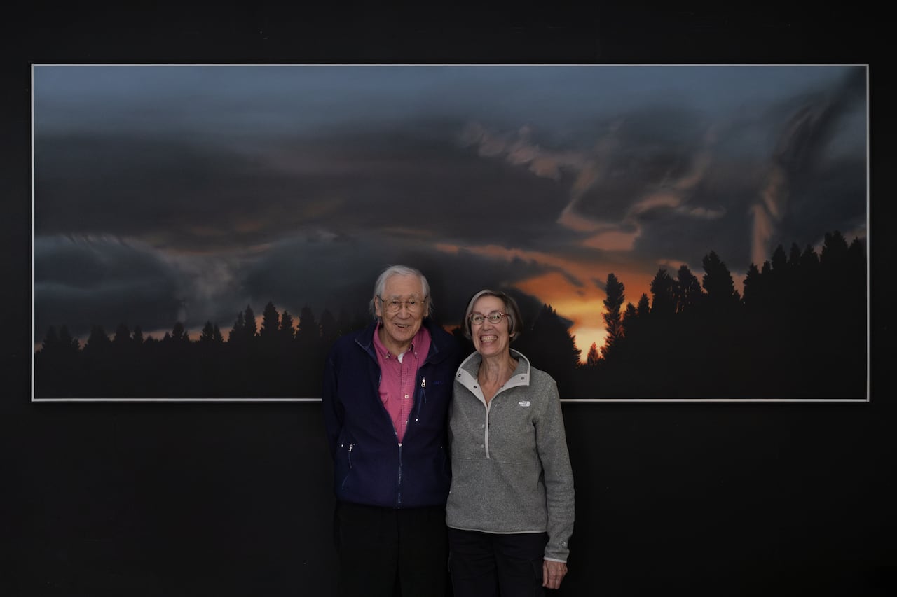 Takao Tanabe and wife Anona Thorne standing in front of a Tanabe landscape painting.