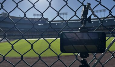 A phone mounted to a tripod behind a fence looking from the bullpen onto the field.