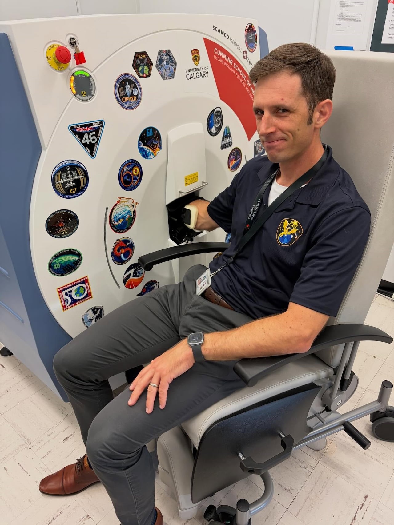 A man sits with his forearm in a large machine.