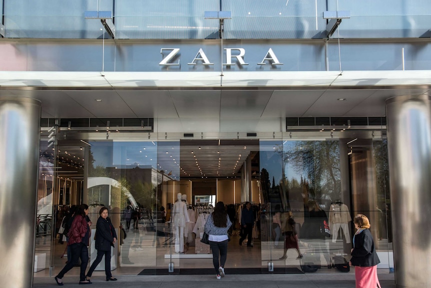 Shoppers mill around the automatic glass doors of the Zara store's imposing chrome and glass exterior.