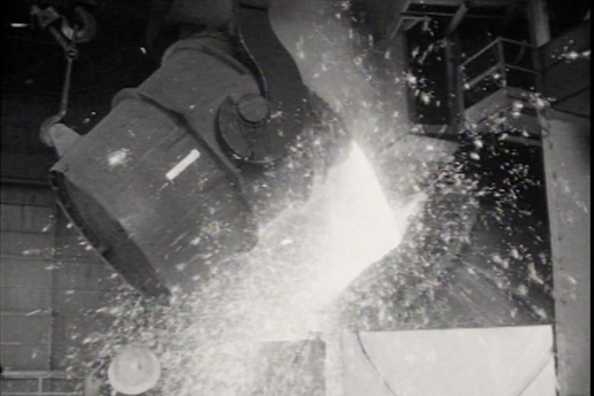 Black and white archival image of the Whyalla Steelworks in operation, showing molten steel being poured out.