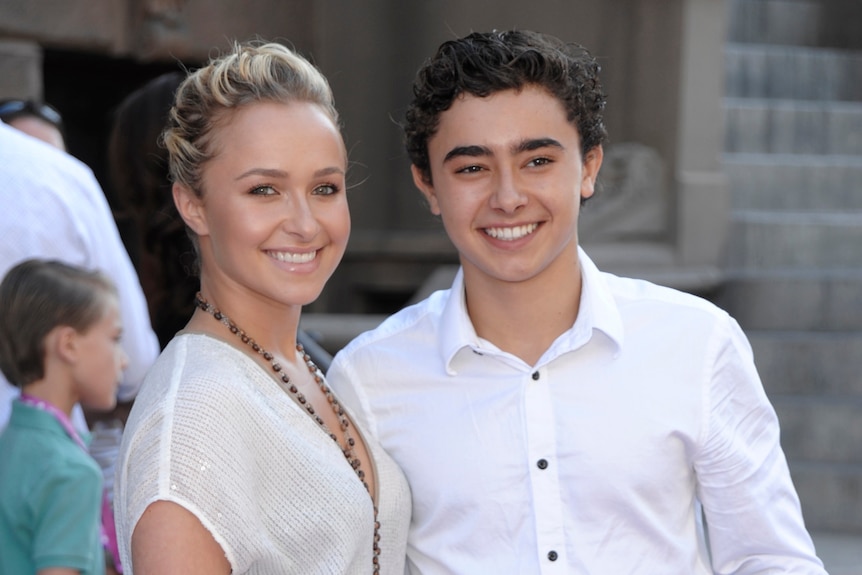 A young blond woman and a young brunette man pose smiling