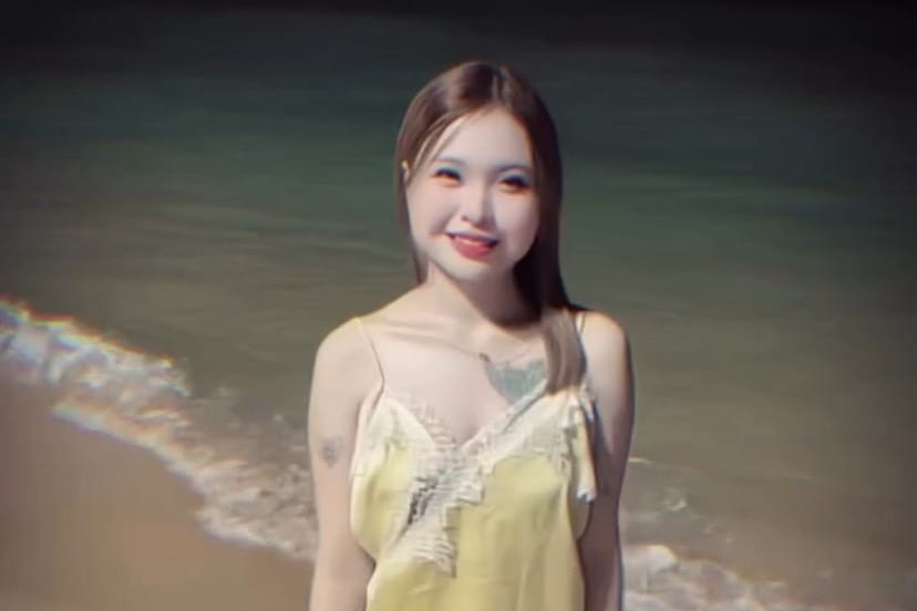 A 17-year-old Thai girl, smiling and standing on a beach.