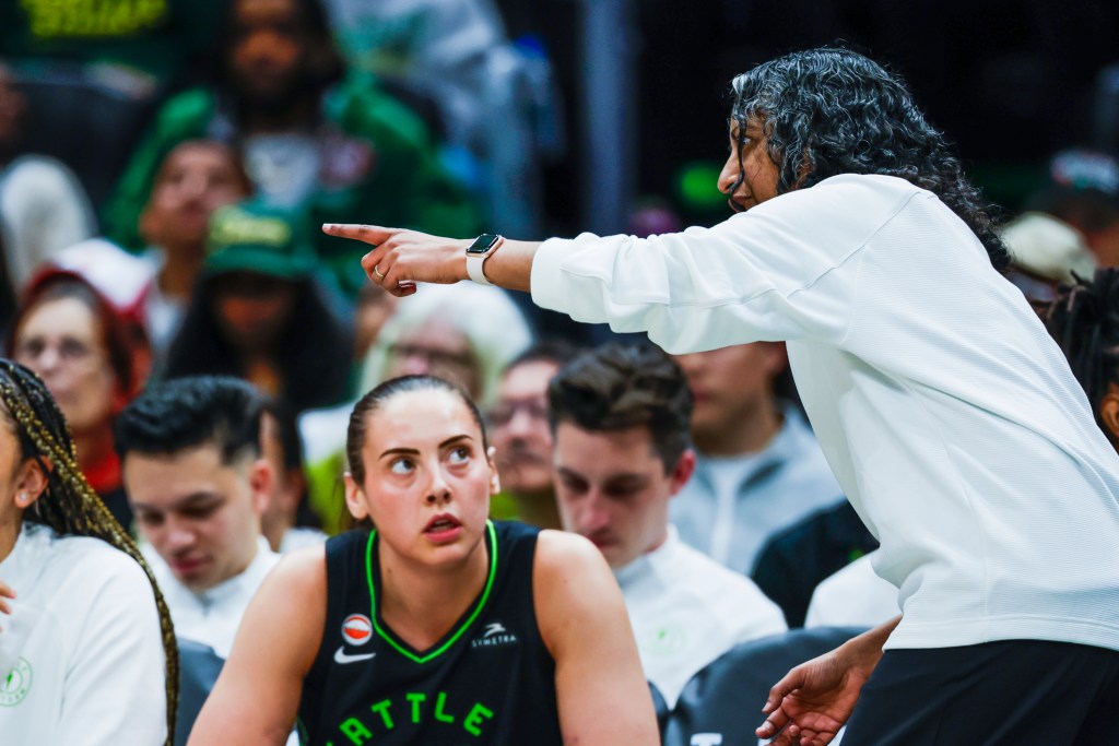 Sonia Raman points to something on the court while Mackenzie Holmes looks and listens to her.
