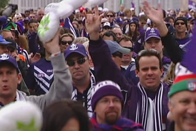 AFL fans march down a city street.