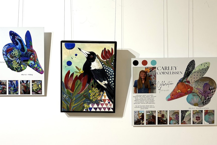two artist profiles of bilby painters hanging either side of a painting of a magpie
