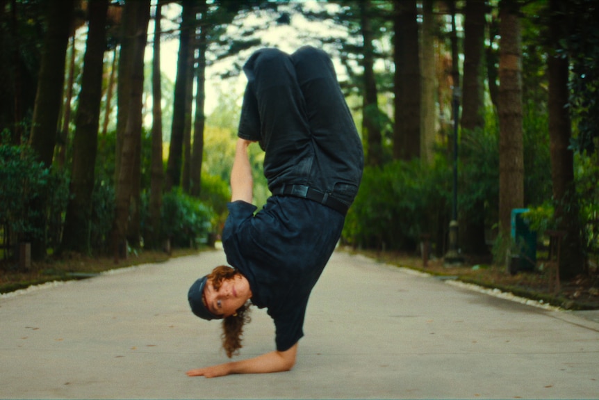 A woman breaking outside with legs in the air and one arm on the ground