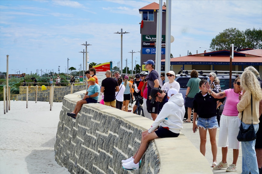 People looking toward beach from elevated footpath 