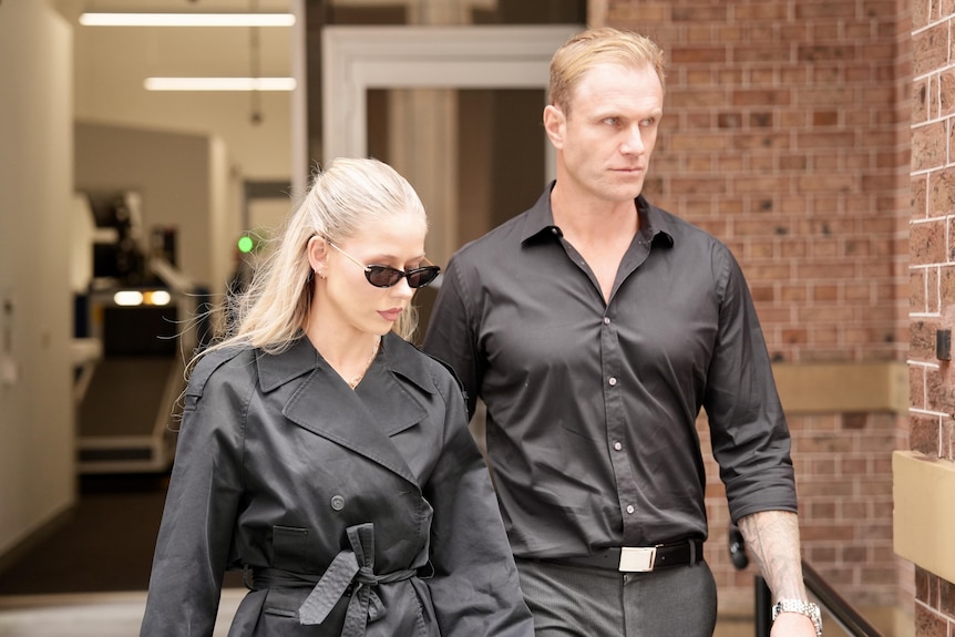 Georgina Cook walks outside court dressed all in black next to a man