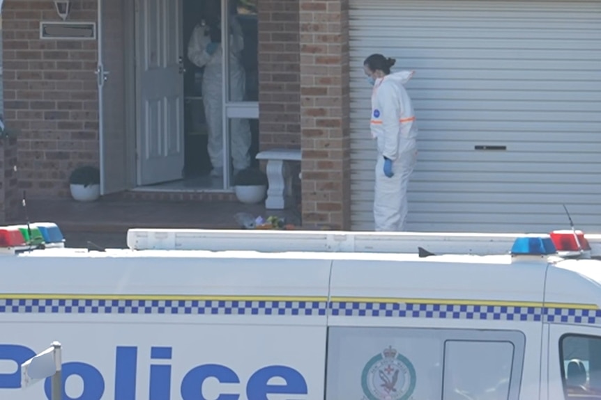 Police in white suits inside light brick home with light-coloured features, police van in front of the car