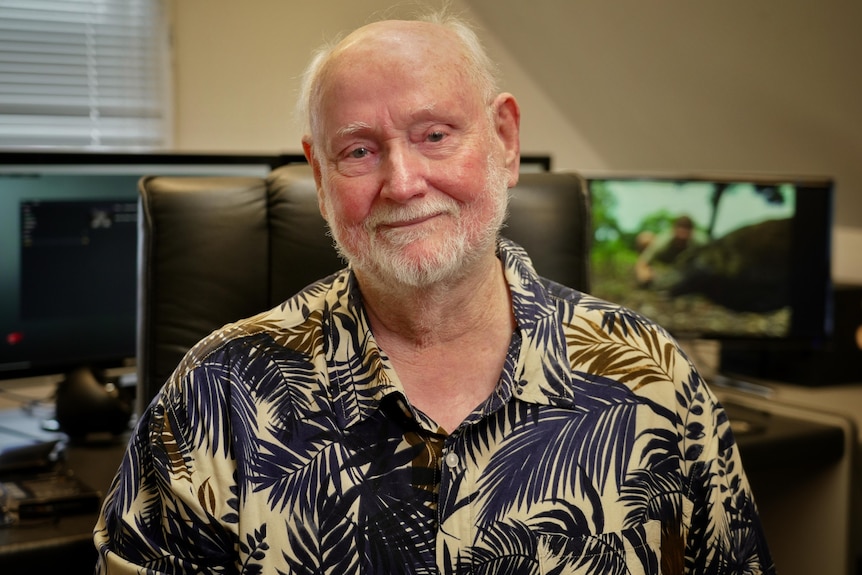 Man looking emotional into camera with editing screens behind him.