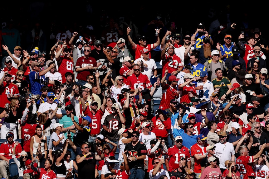 NFL fans celebrate in the stands of the MCG while watching game