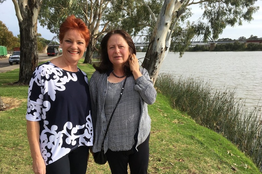 Pauline Hanson in a navy and white shirt standing next to Jennifer Game by a lake.