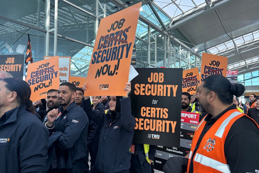 A group of people carry signs calling for better job security.