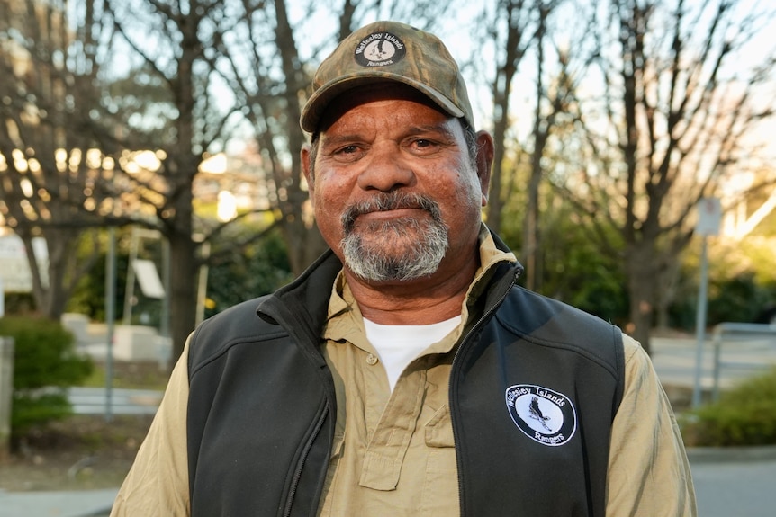 Tommy Wilson, wearing a cap and khaki shirt with a black vest, smiling