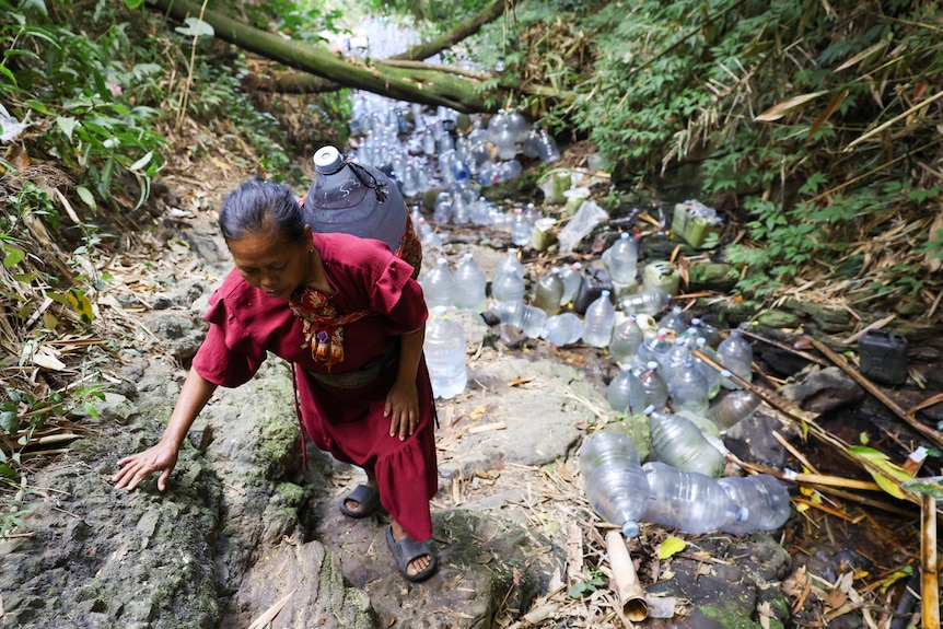 A villager carries a water container to collect spring water in a drought-hit area during the dry season.
