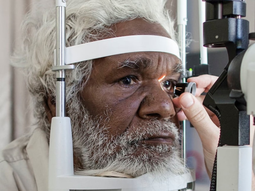 An older indigenous man leans into a head support device so his eyes can be tested.