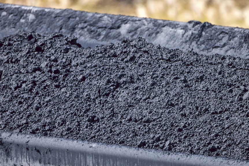 A close up of black rock and material in a dark grey train wagon.