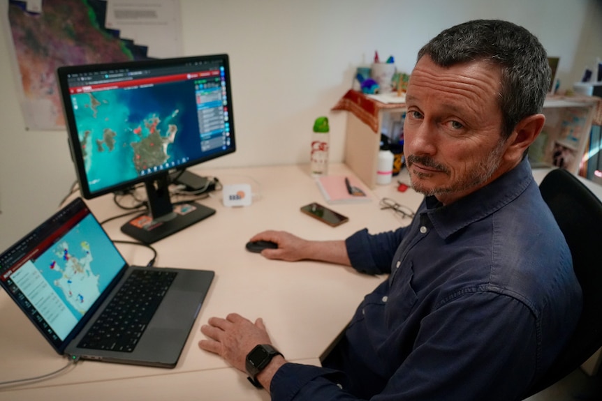Man at desk with satellite maps on two computer screens
