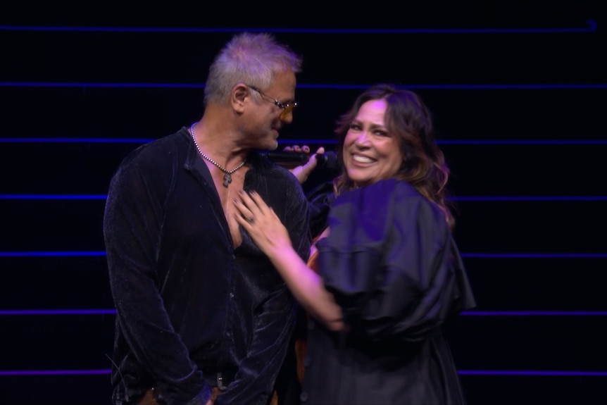 Jon Stevens and Kate Ceberano smile as they stand together.