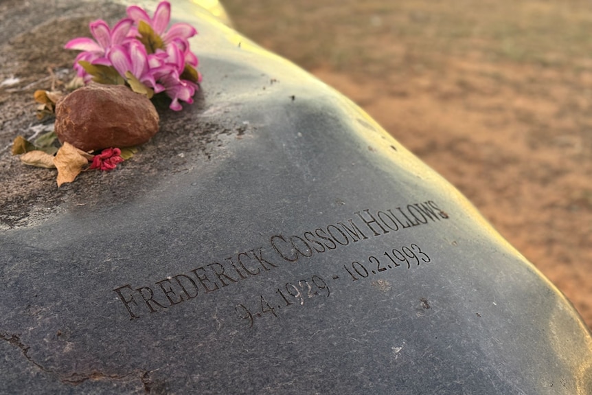 The words 'Frederick Cossom Hollows 9.4.1929 to 10.2.1993' etched on a shiny black rock with flowers on top.