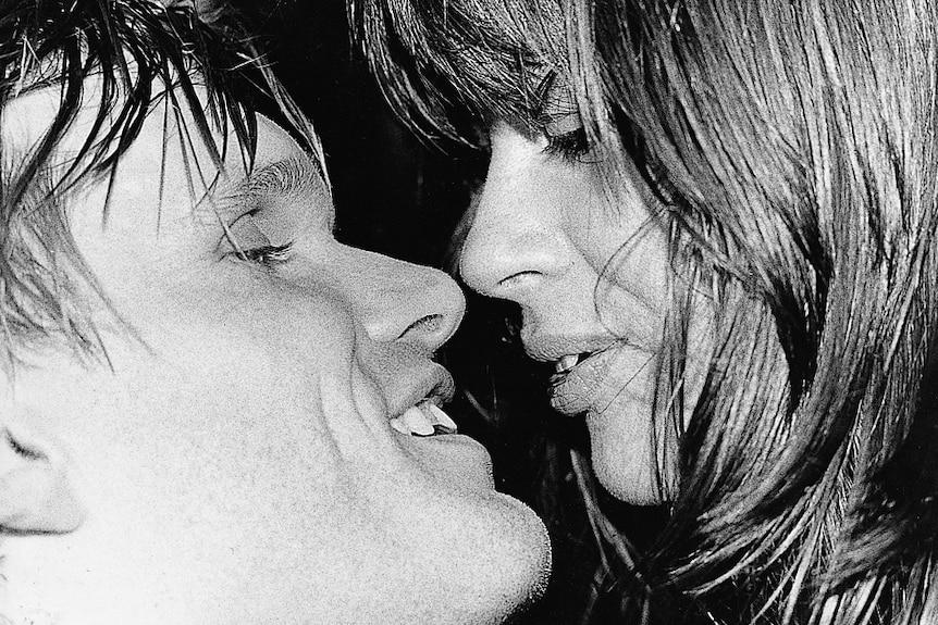 Black and white photo of Divinyls singer Chrissy Amphlett and guitarist Mark McEntee about to kiss.