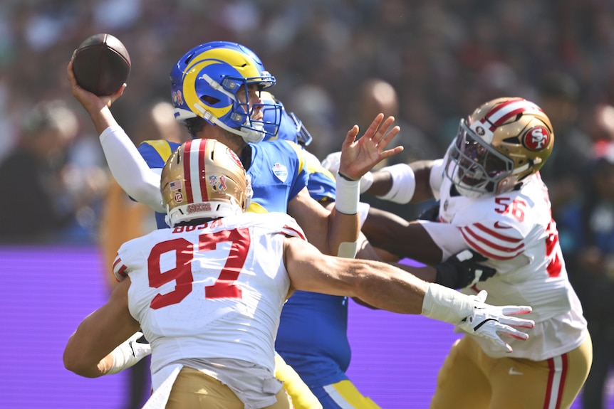 Matt Stafford of the LA Rams throws the ball as the San Francisco 49ers defence swarms him.