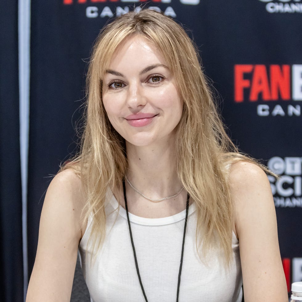 Michelle Mylett michelle mylett sitting at a fan expo canada booth with photos on the table