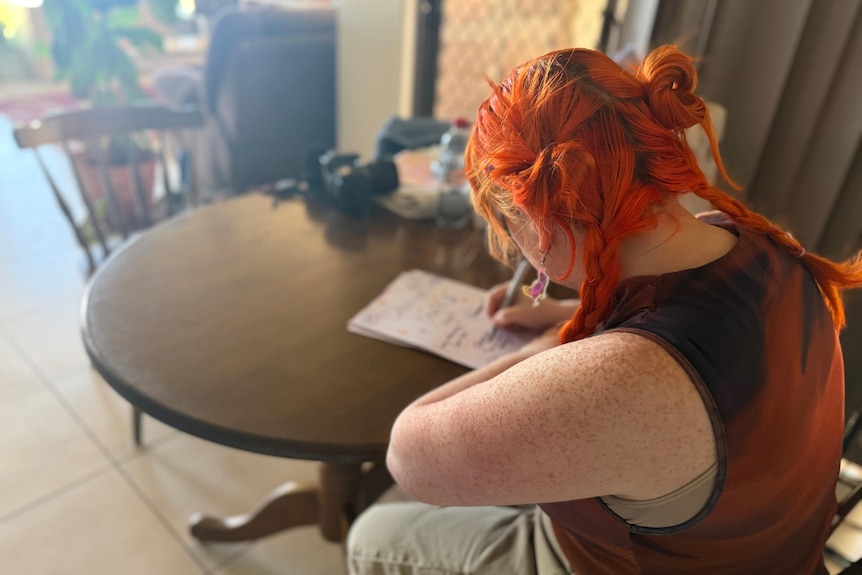 A woman sits at a desk and draws posters