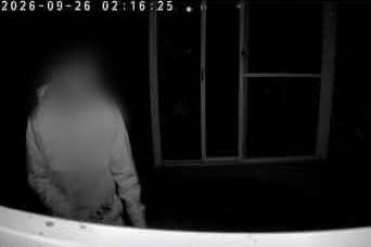 A still image from black and white CCTV footage of a person whose face is blurred.