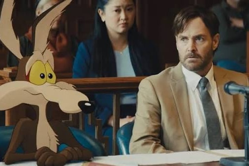 A cartoon coyote sits next to a human lawyer in a courtroom.