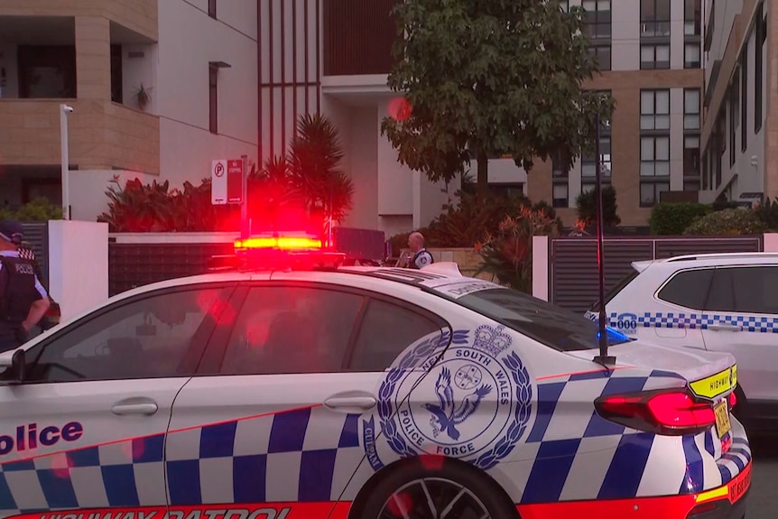 Cop cars with red lights outside an apartment block