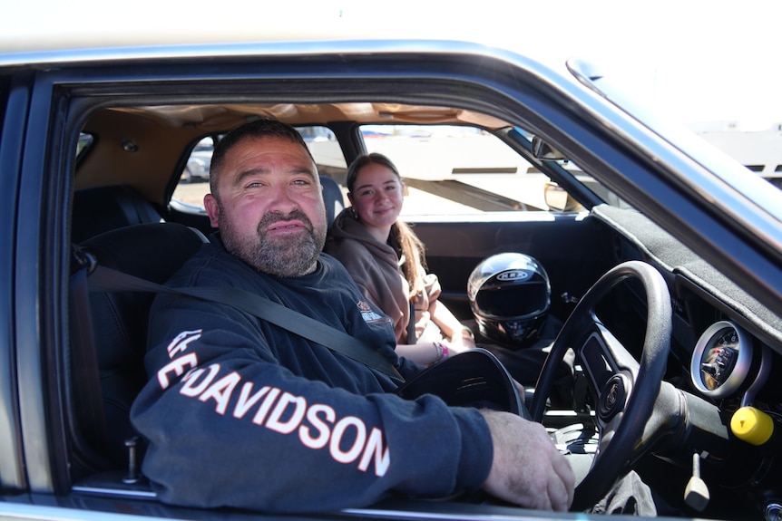 Father in driver's seat of car with daughter on passenger seat smile 