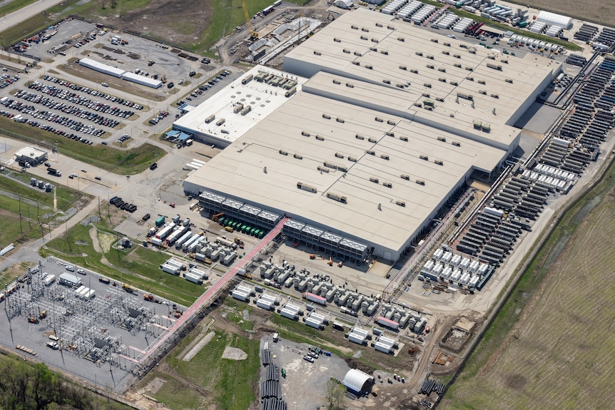 Aerial view of xAI’s Colossus data centre, a large warehouse-like complex surrounded by roads and open land.