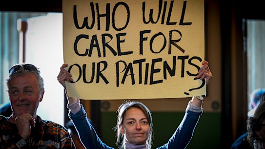 An attendee holds a placard during an emergency public meeting at Fitzroy Town Hall last year about the cohealth closures.