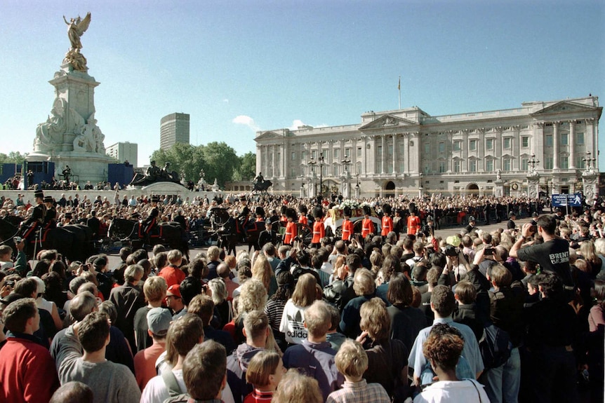 You look from behind a large crowd gathered at the front gates of Buckingham Palace with Princess Diana's coffin passing by.