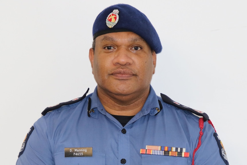 man wearing beret and blue uniform in front of white wall