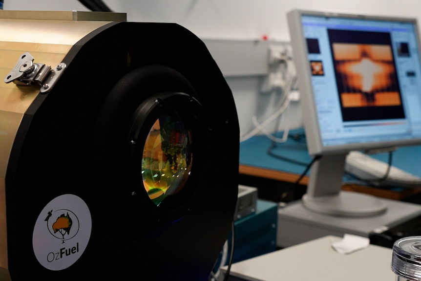 Small telescope in foreground with infrared scan on computer screen in background