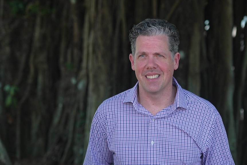 Mark Olsen from Tropical Tourism North Queensland smiling with trees behind him.