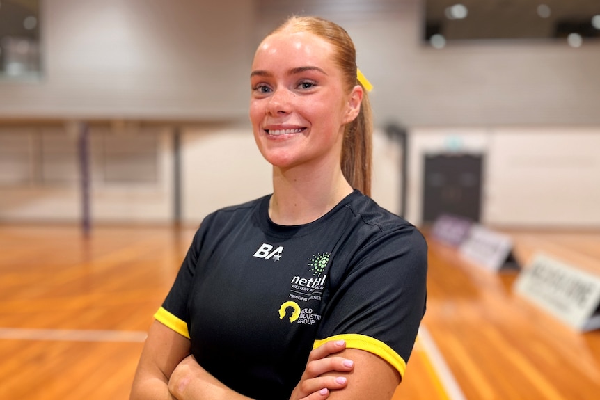 Netballer Scarlet Jauncey poses for a photo smiling with arms folded
