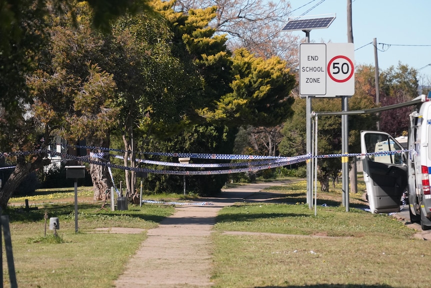 Police tape at a crime scene on a suburban street.
