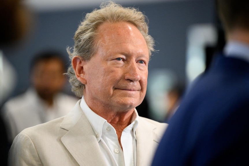 A man in a cream suit speaks to people in a meeting