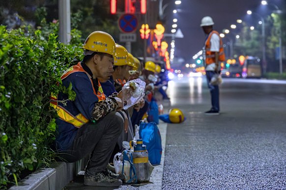 Migrant workers eat breakfast while waiting in Majuqiao for a shuttle bus to take them to a construction site.
